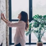 リビングでタブレットから室温と照明をまとめて調整する居住者