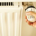 壁の温度調節器を操作する住まい手