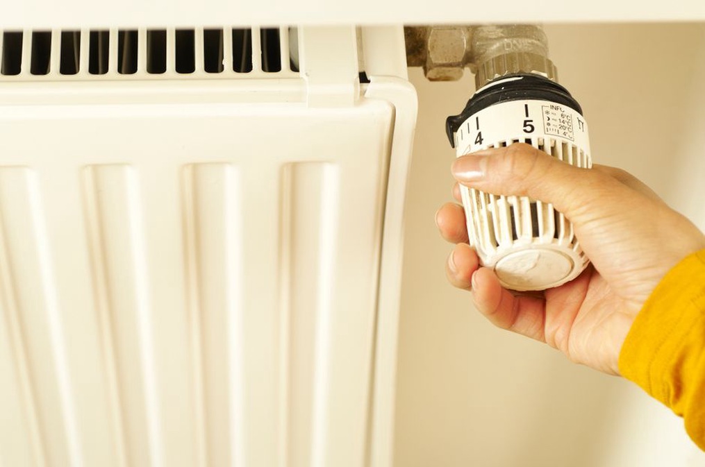 壁の温度調節器を操作する住まい手