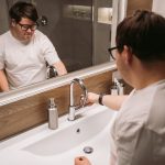 洗面台下の状態をスマートフォンで記録する様子